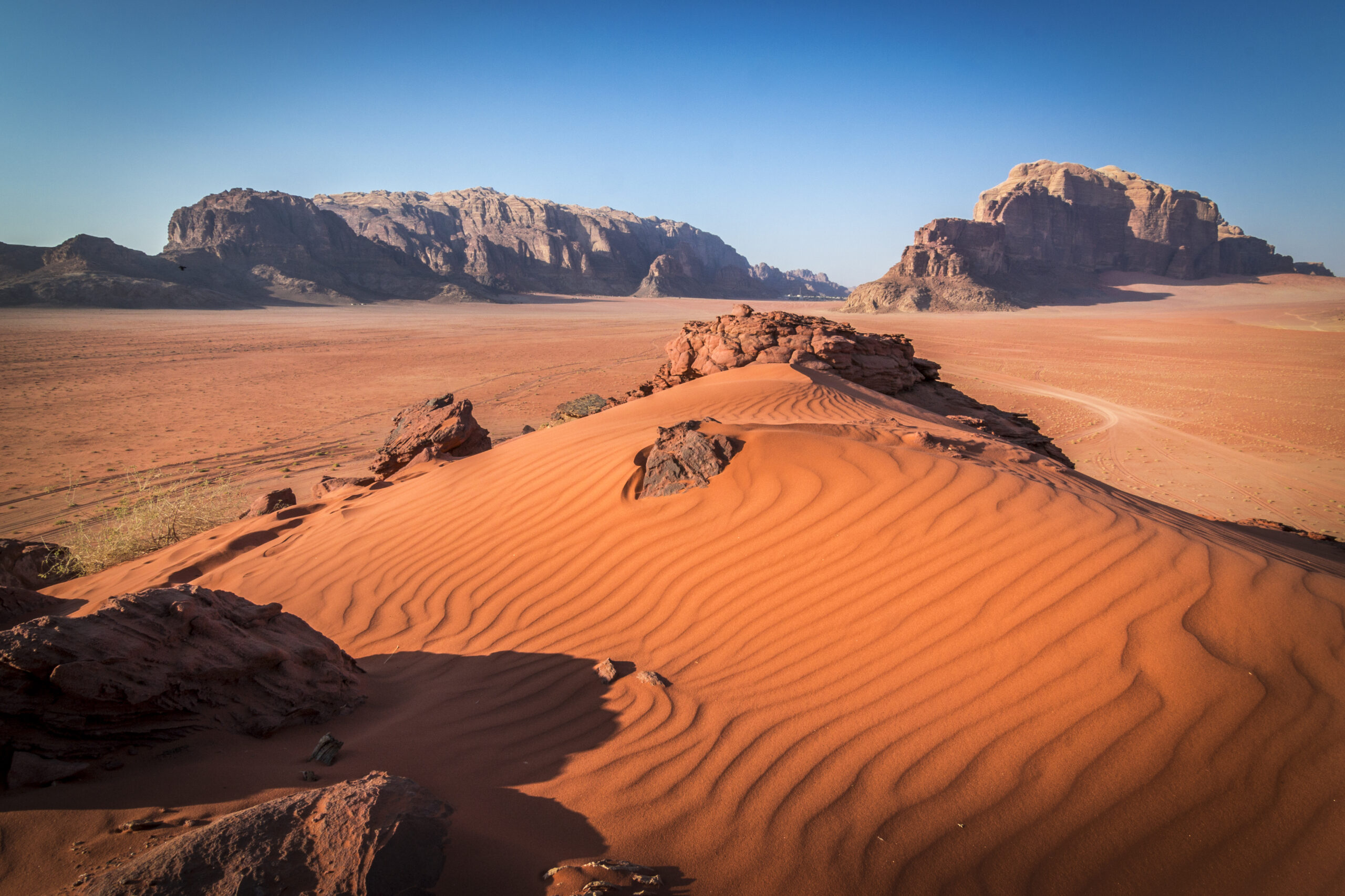 Red sand in Wadi Rum. Middle East, Travel, No People, Scenics, Heat - Temperature, Red, Wadi Rum, Jordan - Middle East, Arabia, Sunlight, Rock - Object, Sand, Sand Dune, Desert, Landscape, Sun, blue sky, UNESCO World Heritage Site.